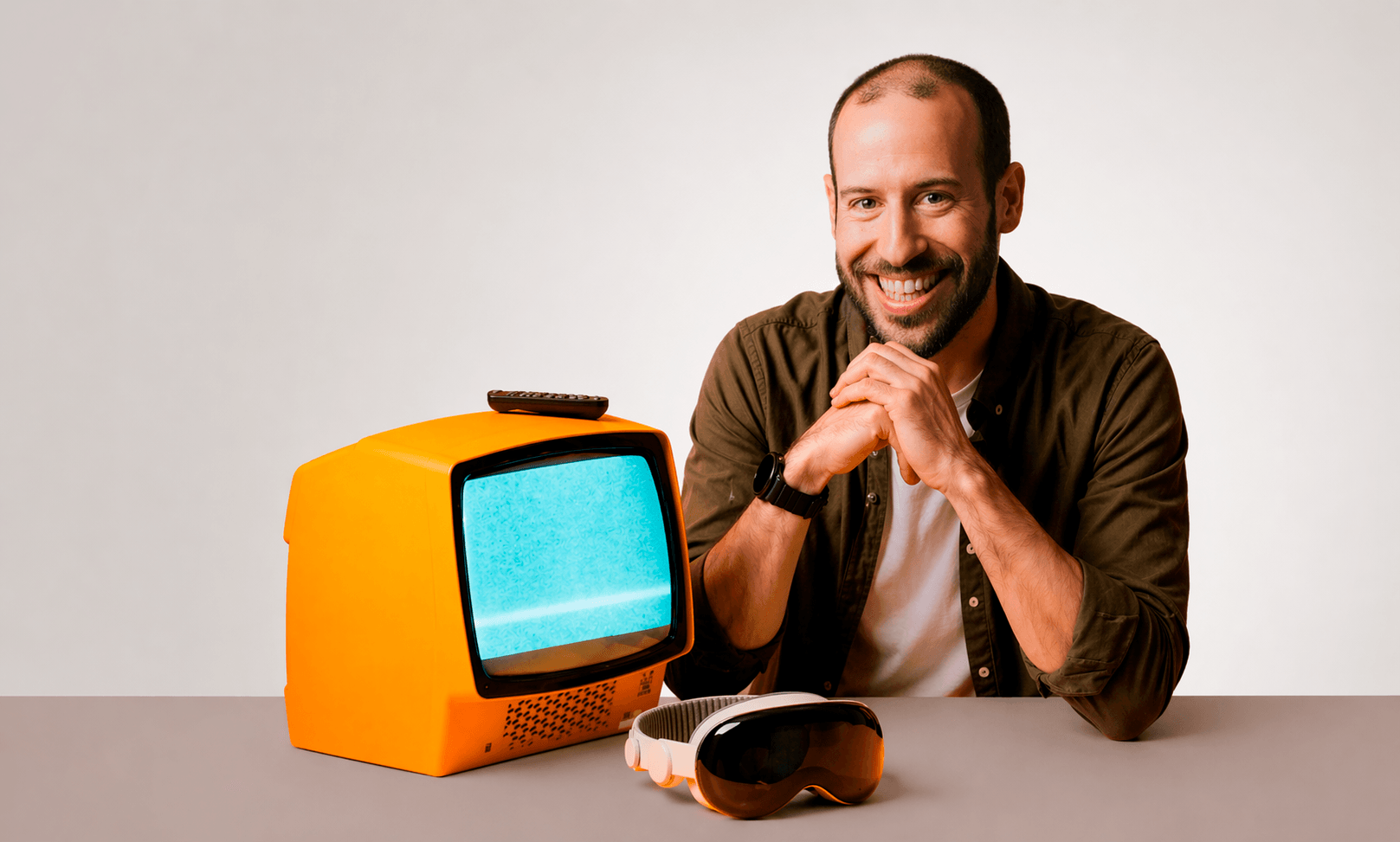 Javier Escorihuela sonriente junto a un televisor naranja de los años setenta y unas gafas de realidad mixta